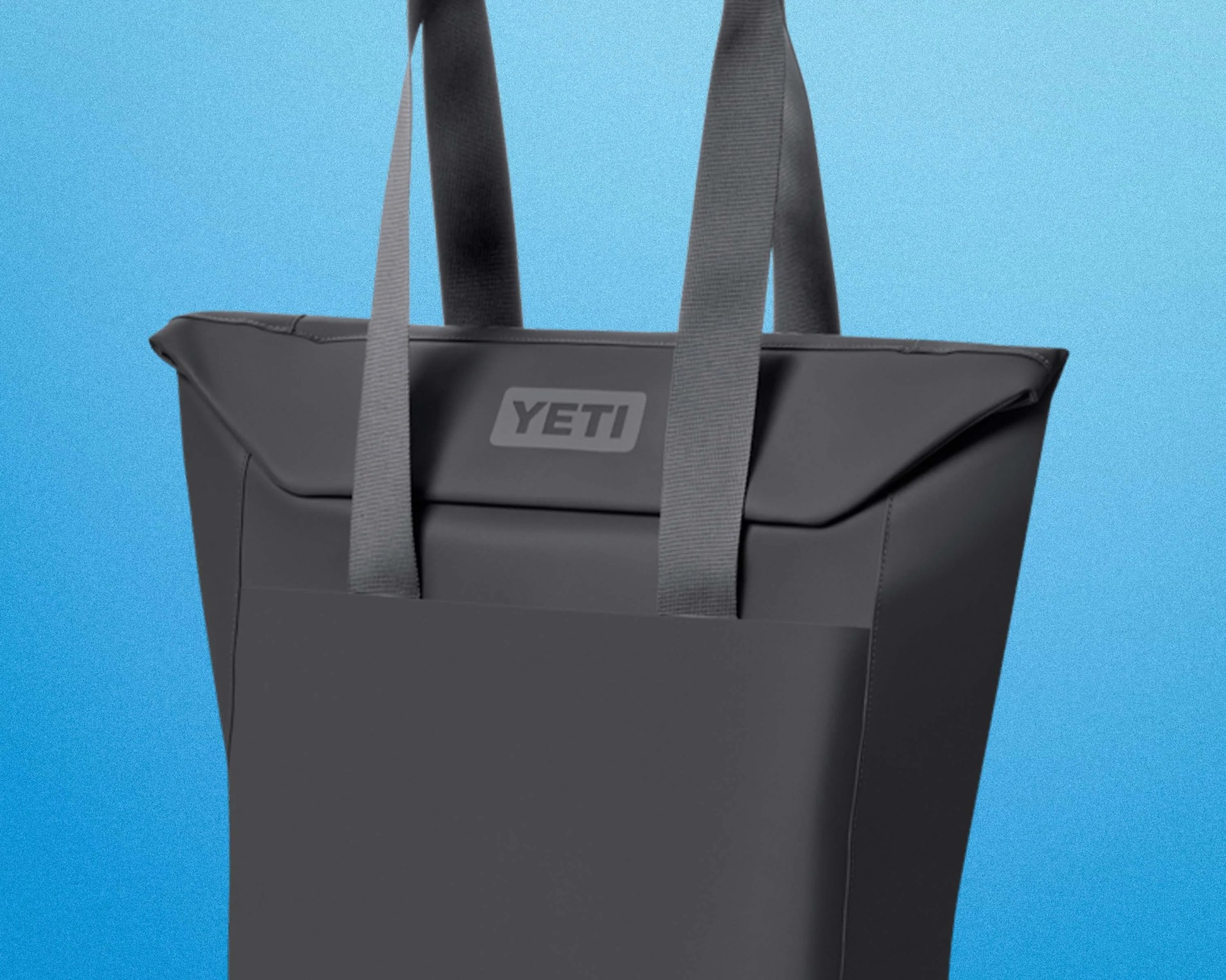 Black YETI tote bag with wide gray handles against a blue background.