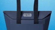 Navy blue YETI tote bag with black handles against a blue background.