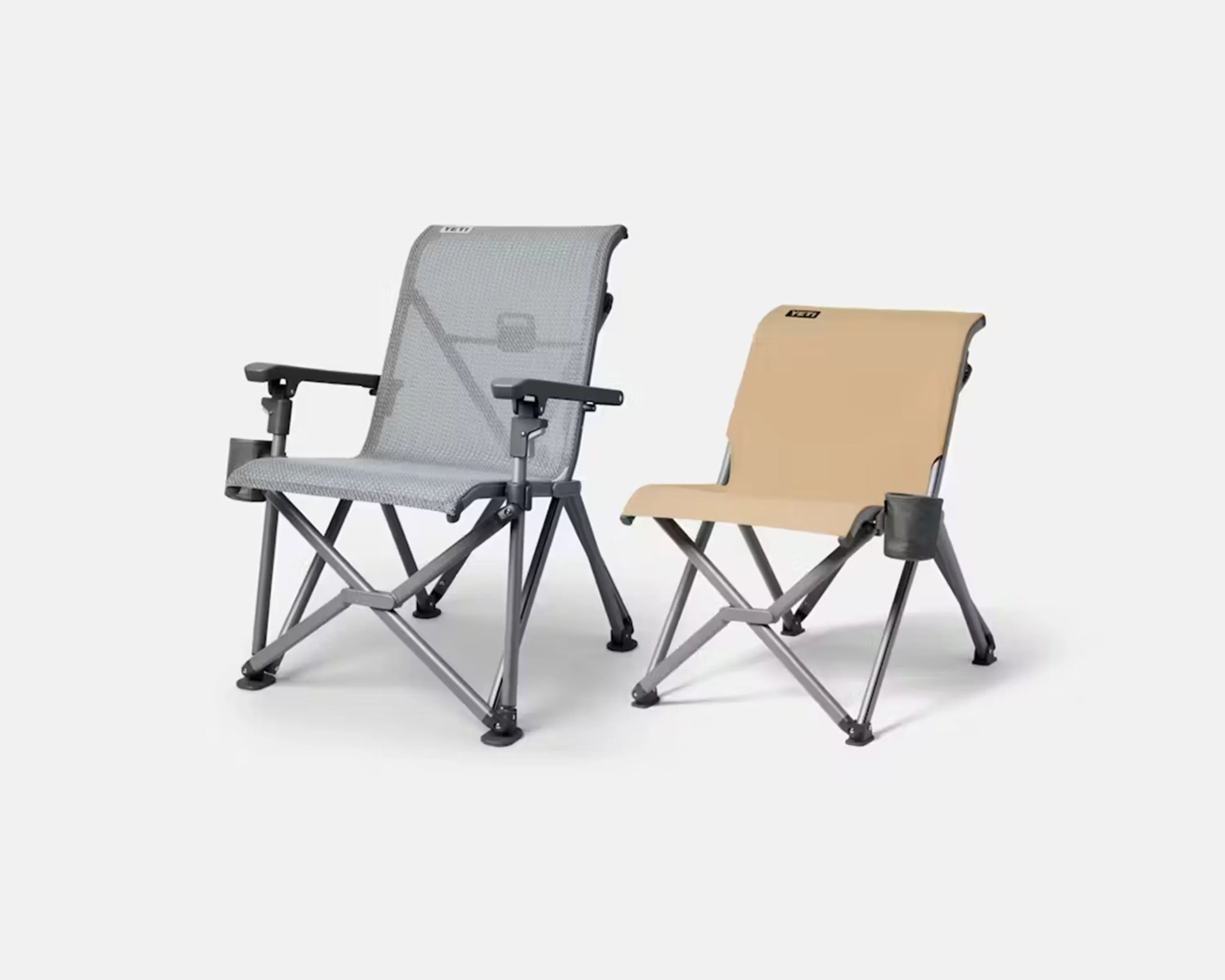 Two foldable camping chairs, one gray with armrests and cup holder, and one beige without armrests, both with metal frames.