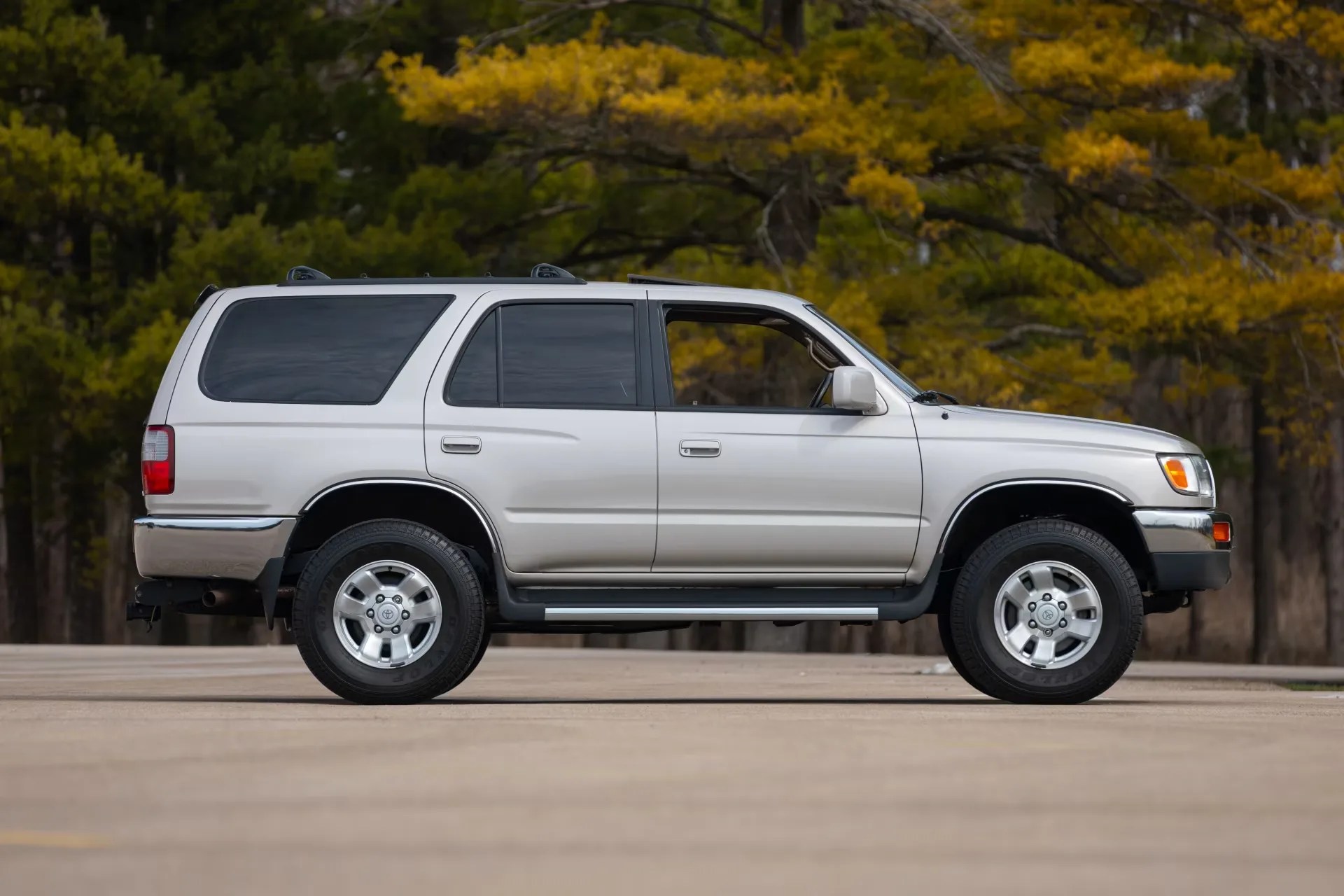 Silver Toyota SUV with tinted windows parked on a concrete surface with trees in the background.