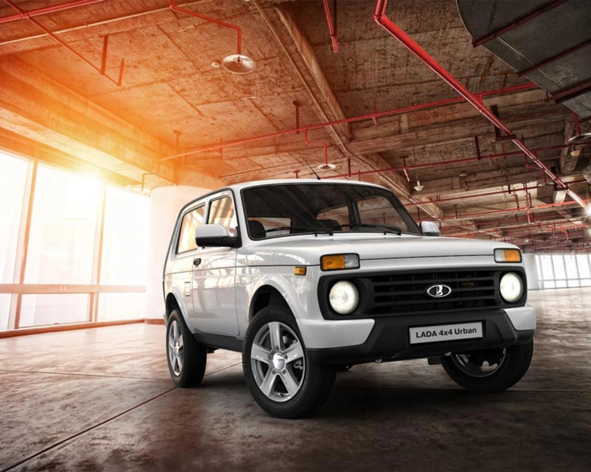 White LADA 4x4 Urban SUV parked inside a spacious industrial building with concrete floors and red ceiling pipes.
