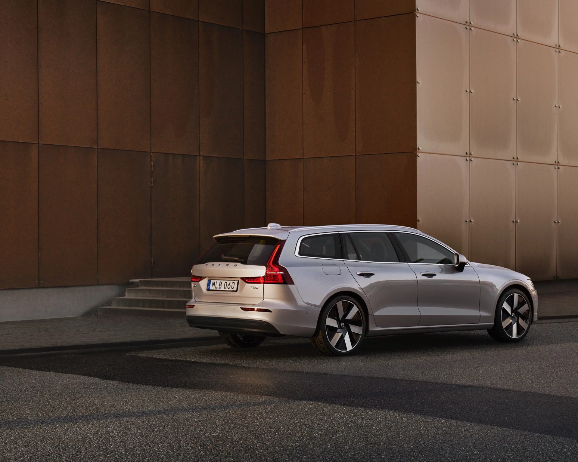 Silver Volvo station wagon parked near a modern building with brown and beige panel walls.