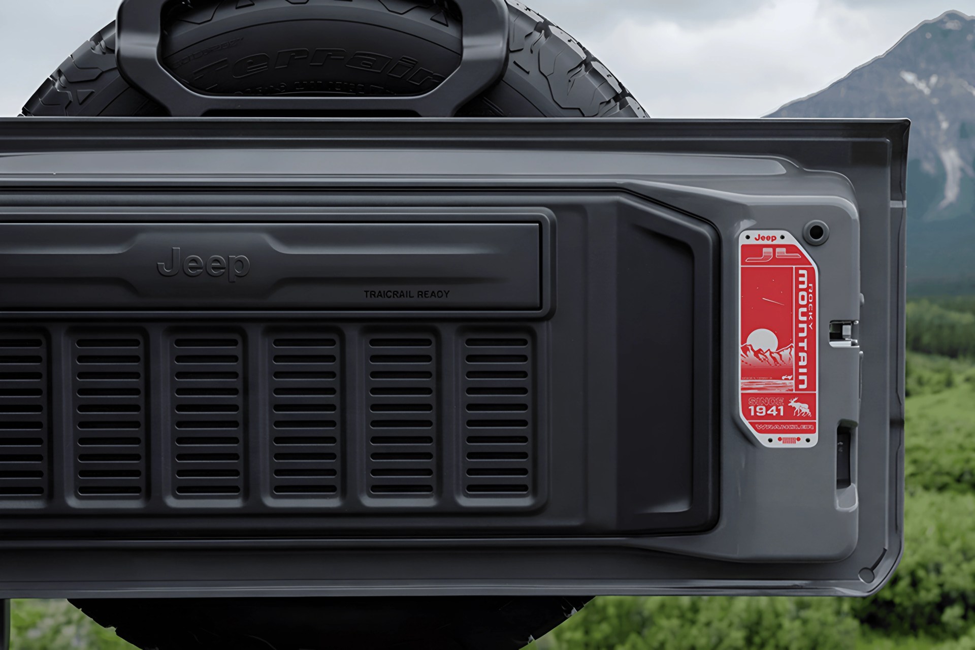 Rear tailgate of a Jeep vehicle with a spare tire mounted above and a red "Rocky Mountain" decal on the side.
