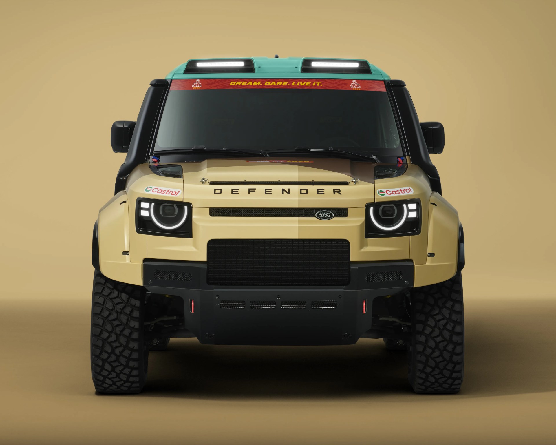 Front view of a beige Land Rover Defender with black accents, LED headlights, and a green roof with roof lights.