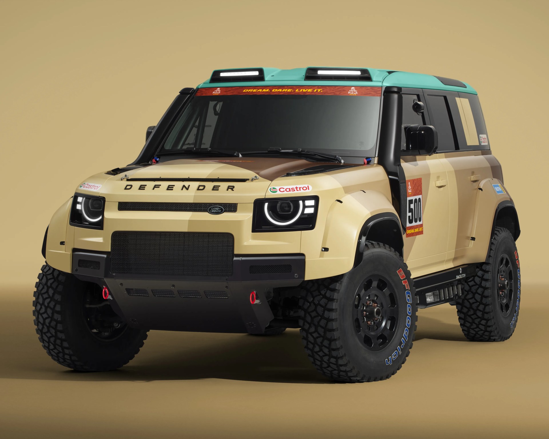 Beige Land Rover Defender with black trim, off-road tires, and turquoise roof against a beige background.