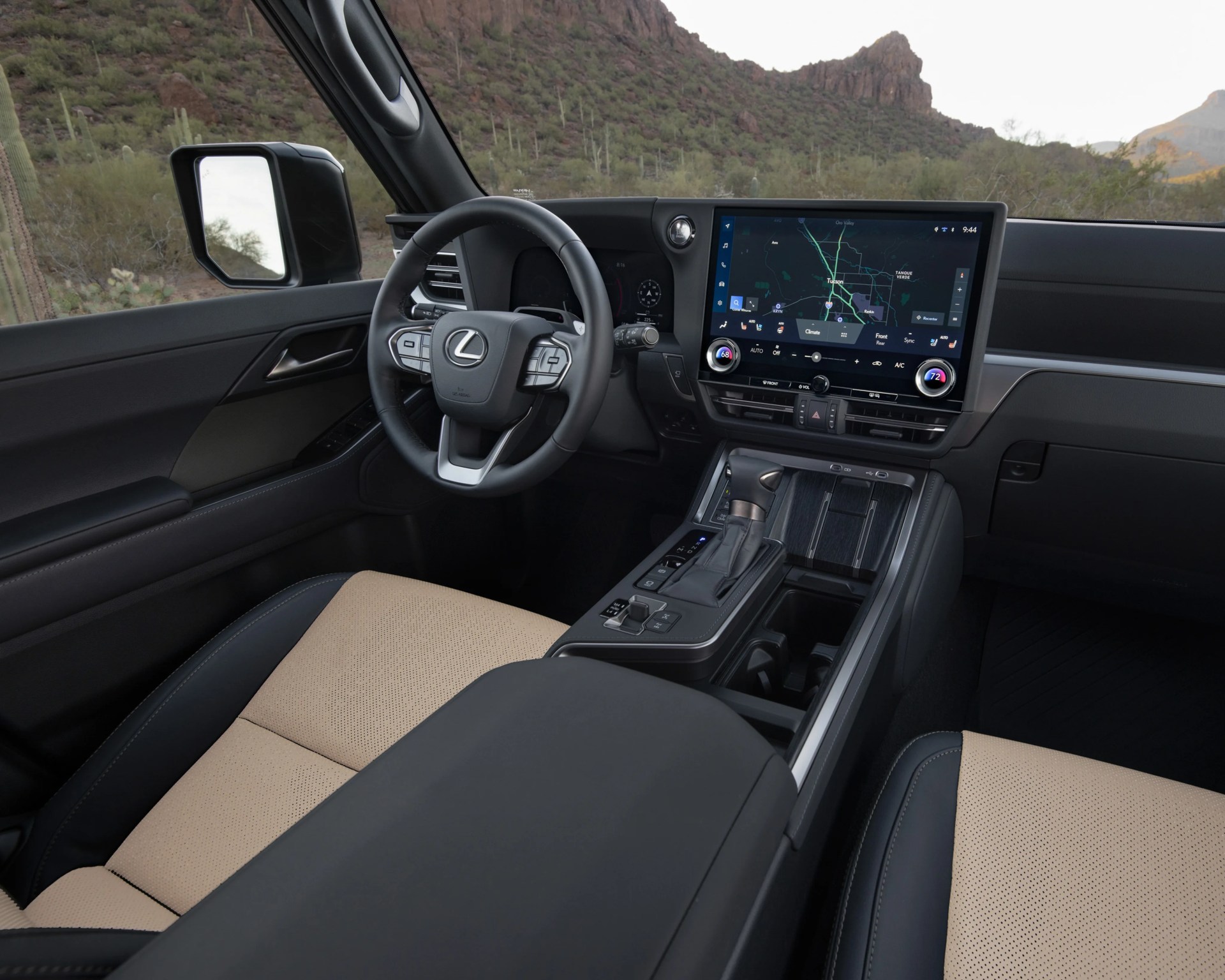 Lexus car interior with black leather steering wheel, beige perforated seats, and large touchscreen display showing navigation.
