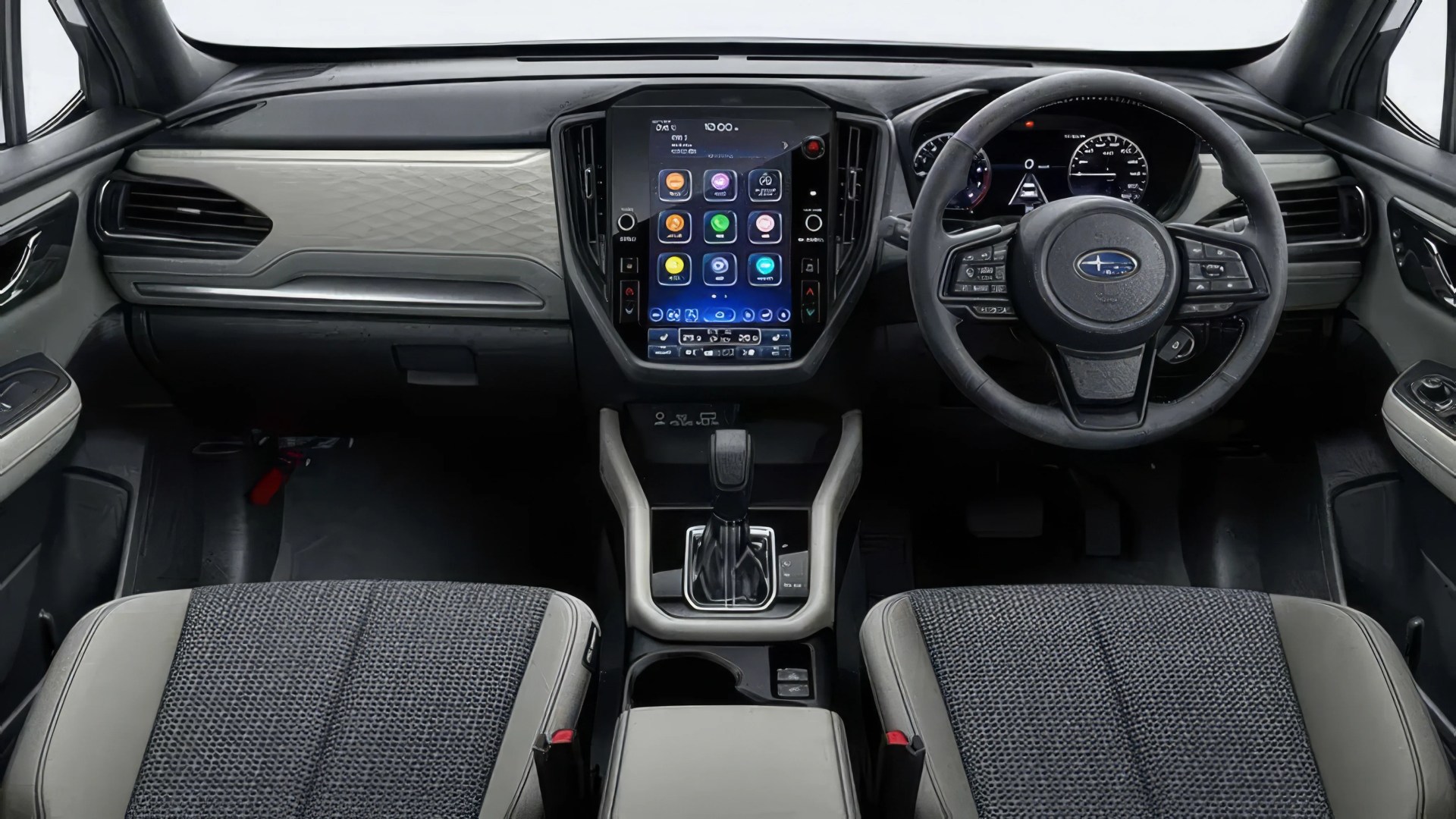 Car interior with a central touchscreen display, black steering wheel with Subaru logo, and two-tone fabric and leather seats.