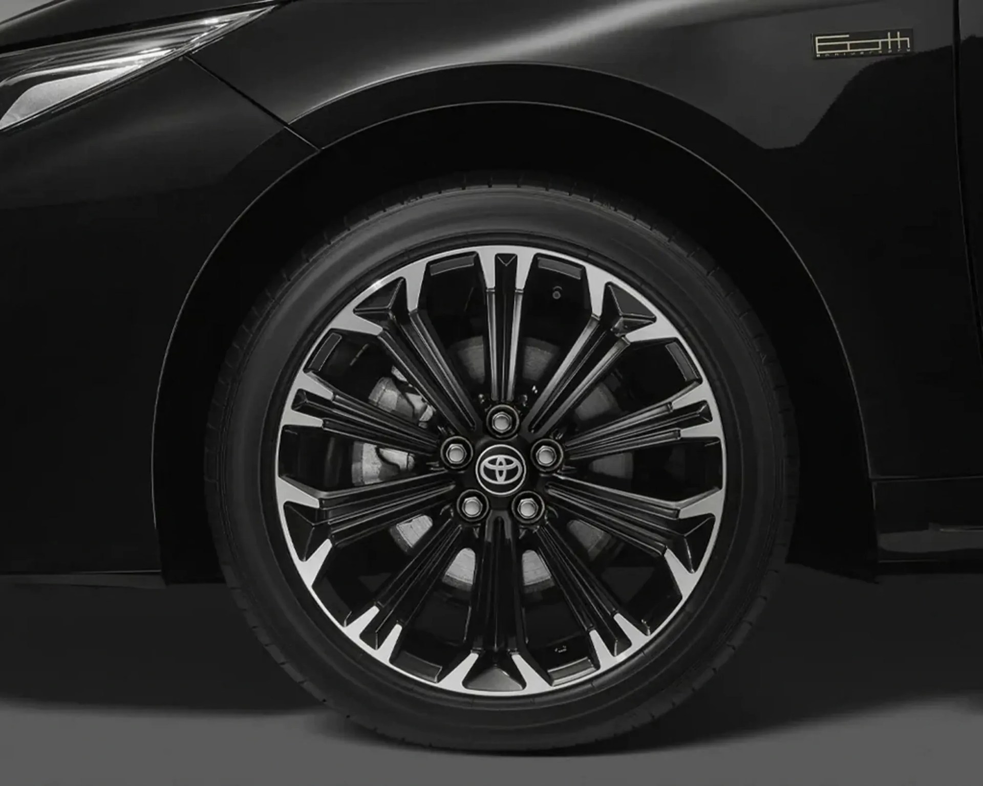 Black and silver multi-spoke Toyota alloy wheel on a black car.