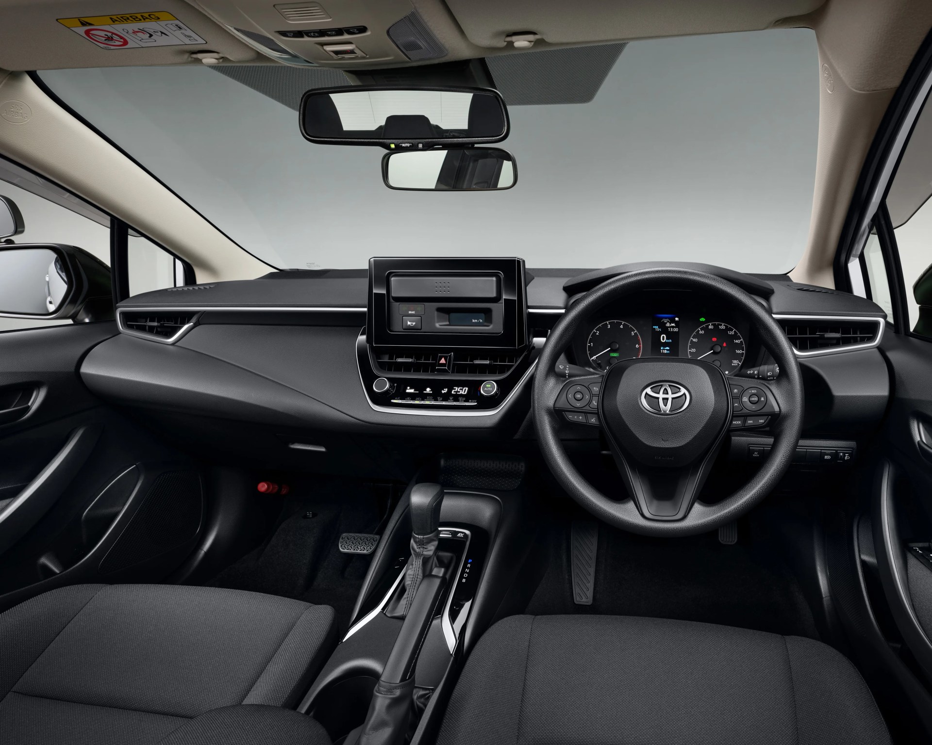 Black and beige Toyota car interior with digital dashboard, touchscreen display, and automatic gear shift.