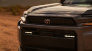Front grille and hood of a dark gray Toyota vehicle with LED lights on a dirt road.