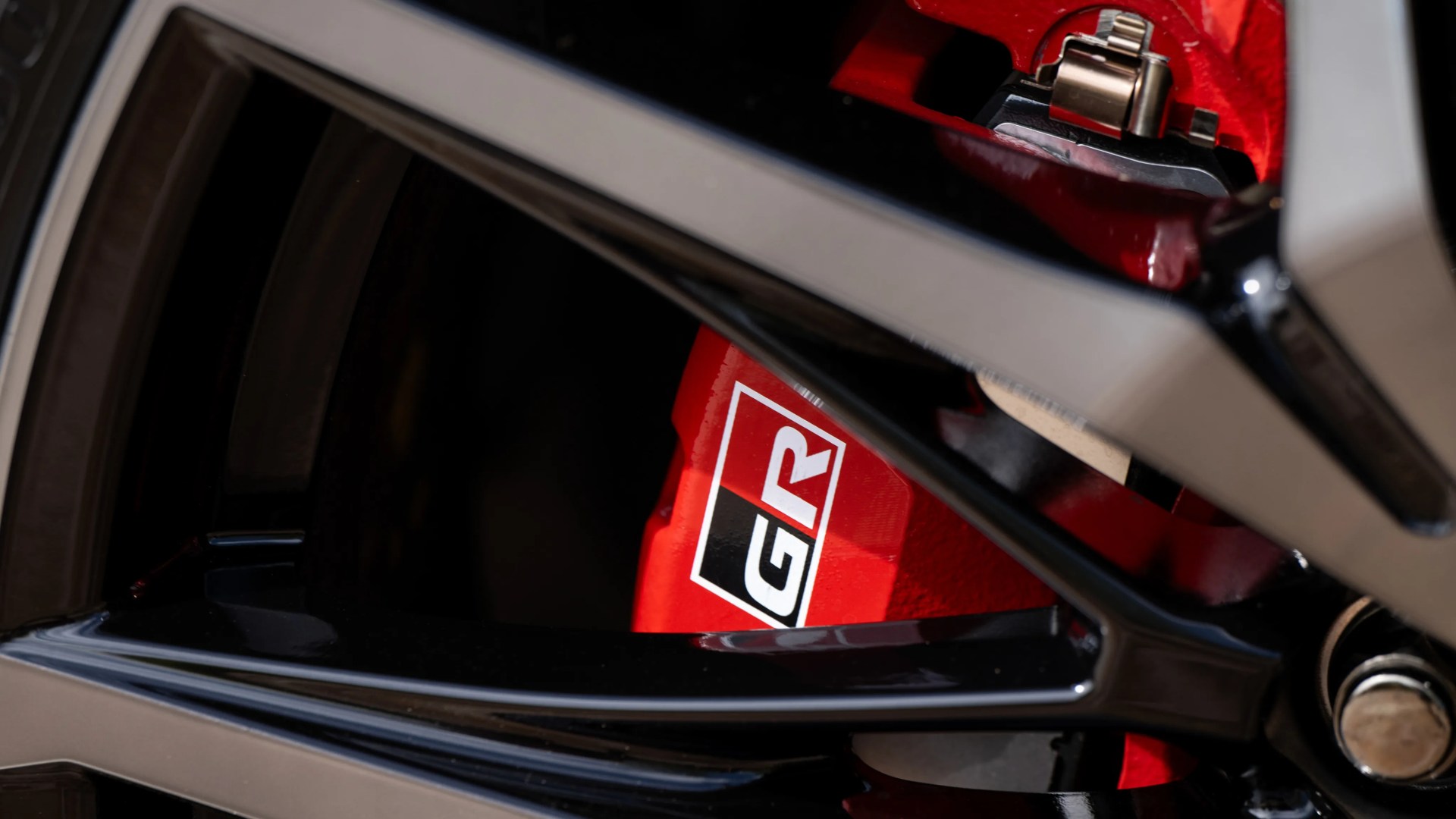 Close-up of a red GR brake caliper behind a black alloy wheel.