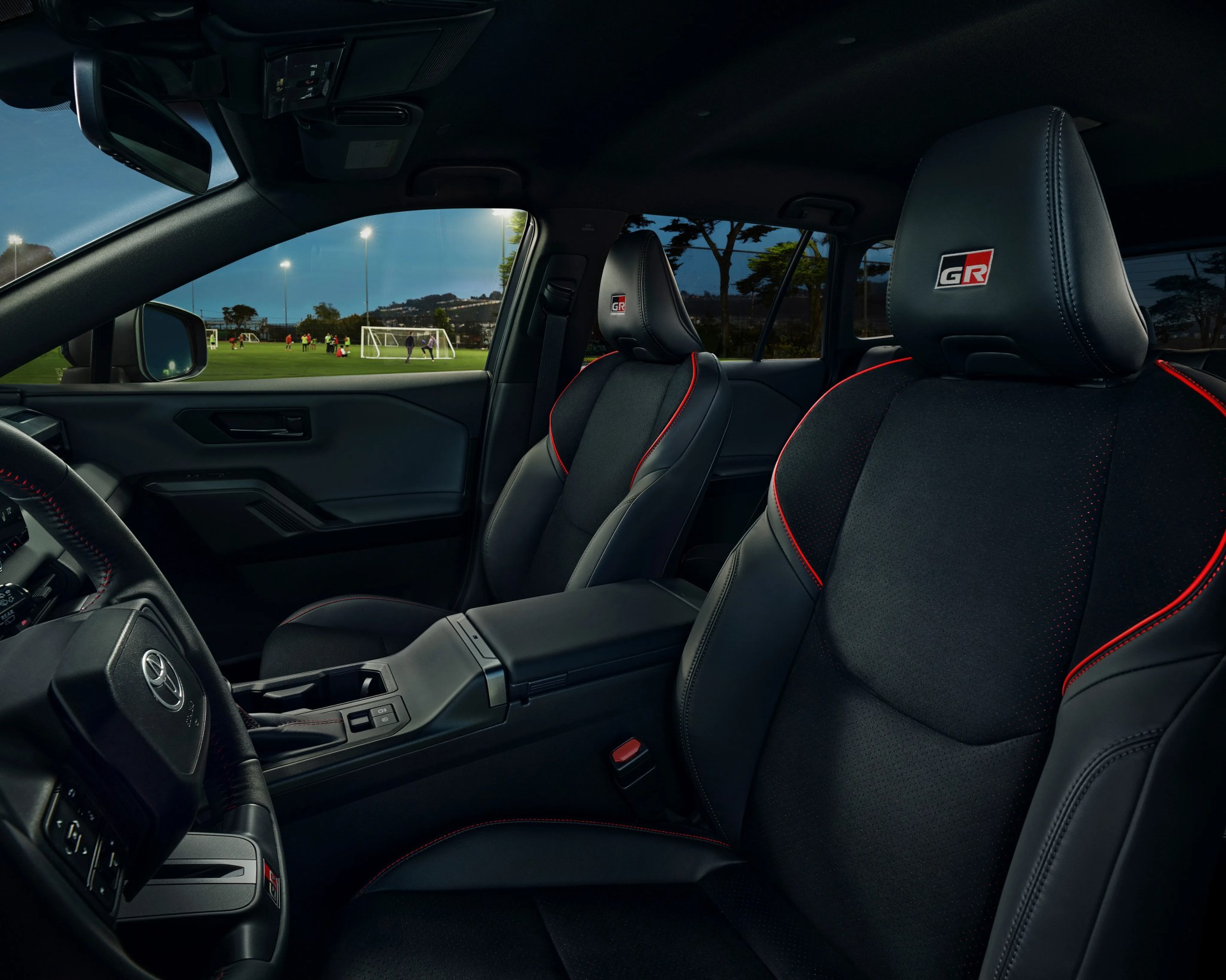 Black leather car seats with red stitching and GR logo on headrests inside a Toyota vehicle.
