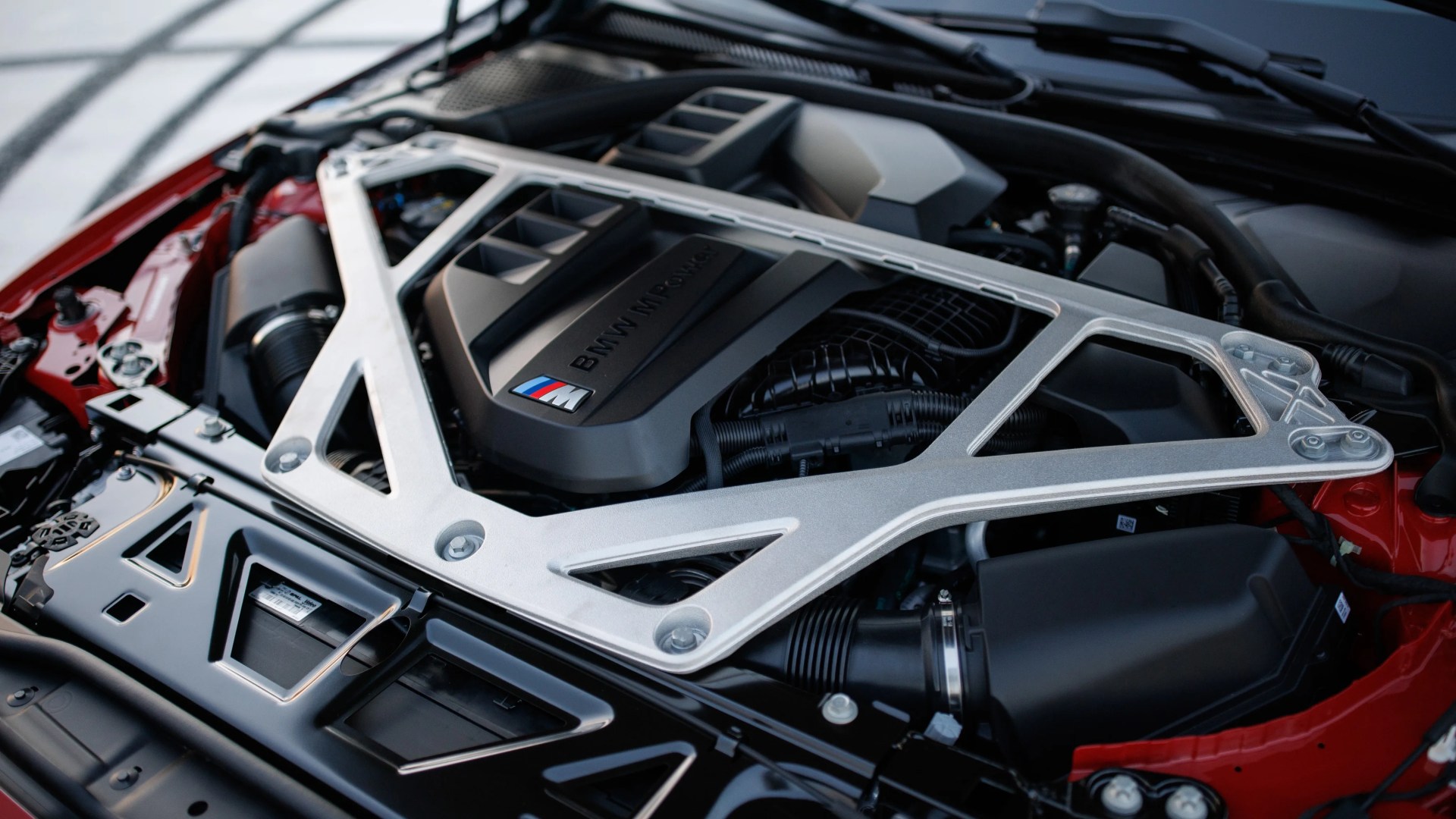 BMW M Power engine with silver strut brace in a red car.