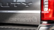 Close-up of a gray truck tailgate with embossed "UTY" and "carhartt" logo next to a red taillight.