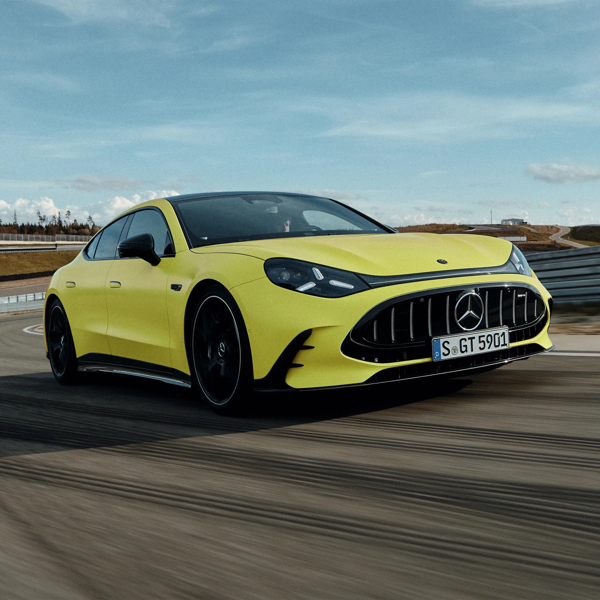 Yellow Mercedes-AMG GT 4-door coupe with black accents driving on a racetrack.