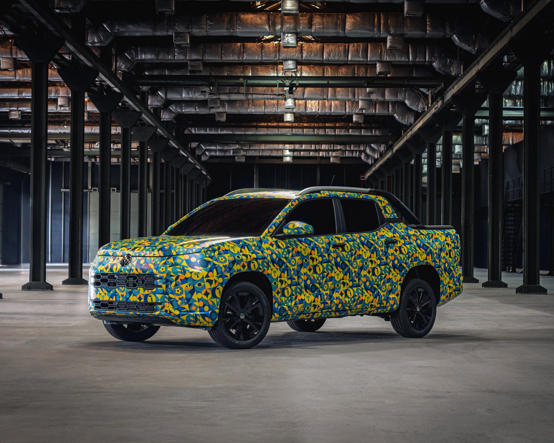 Pickup truck with colorful blue and yellow geometric pattern parked inside a large industrial warehouse.
