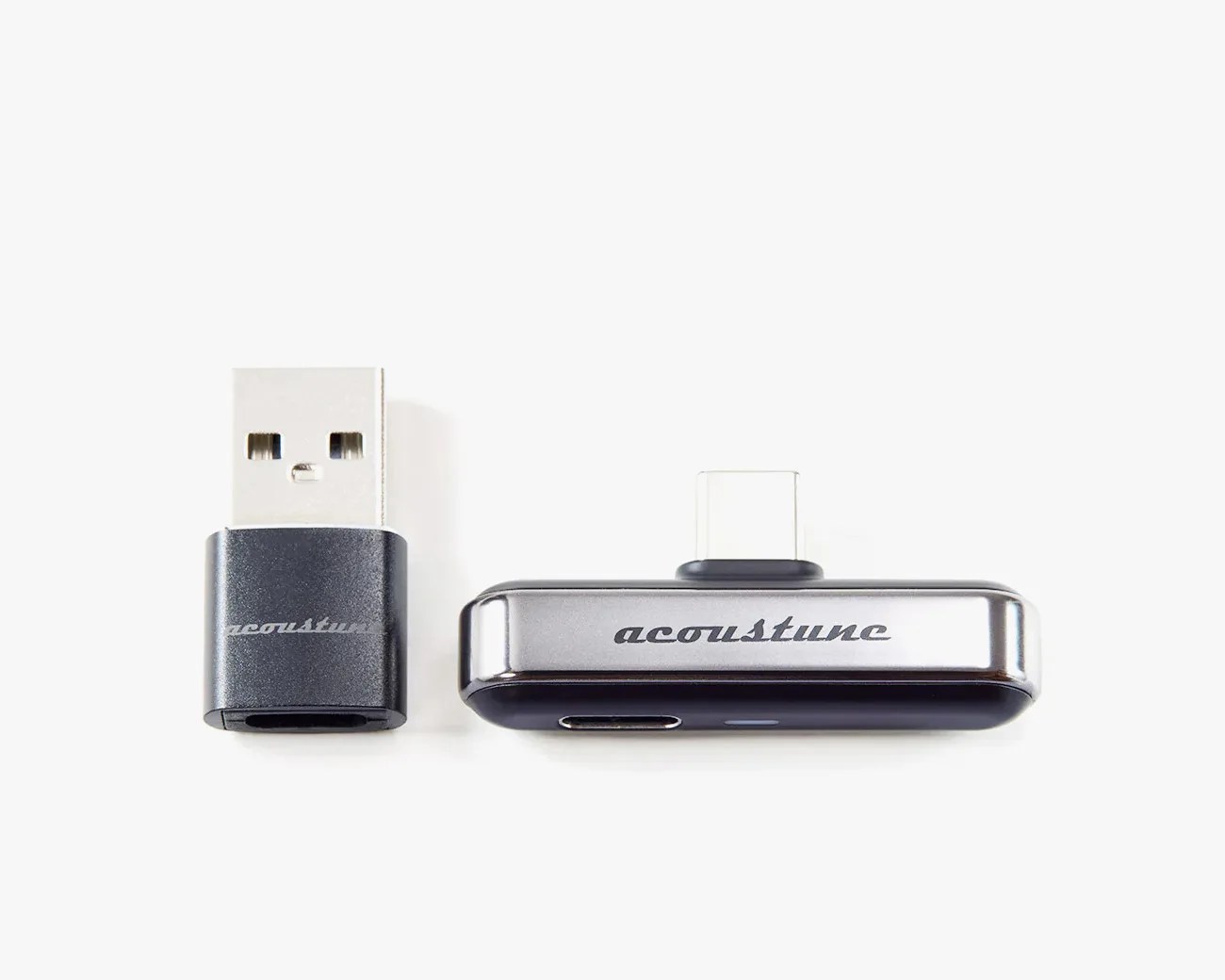 Two small black and silver Acoustune USB adapters, one with a USB-A connector and the other with a USB-C connector.
