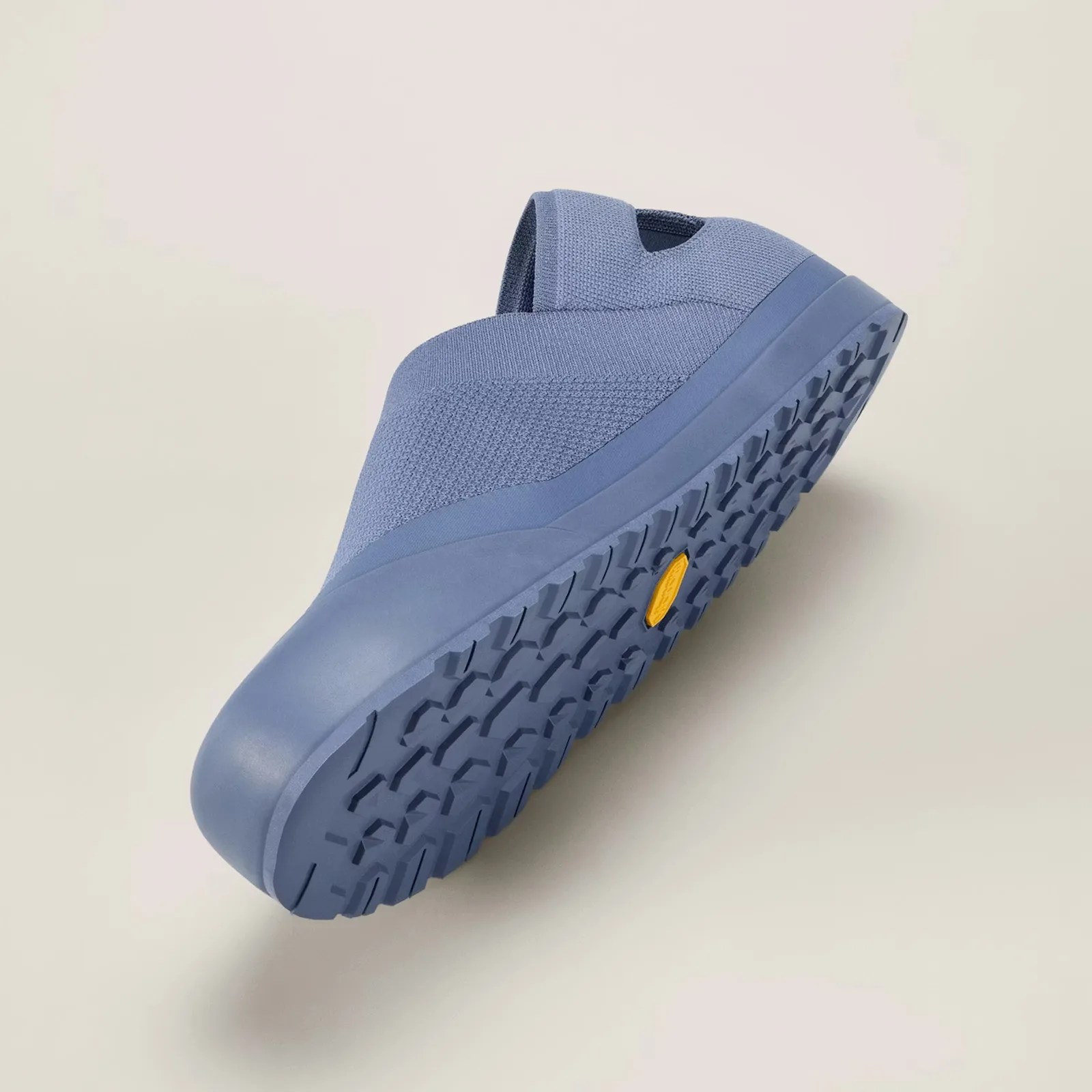 Blue slip-on shoe with textured knit upper and rugged tread sole featuring a yellow logo.