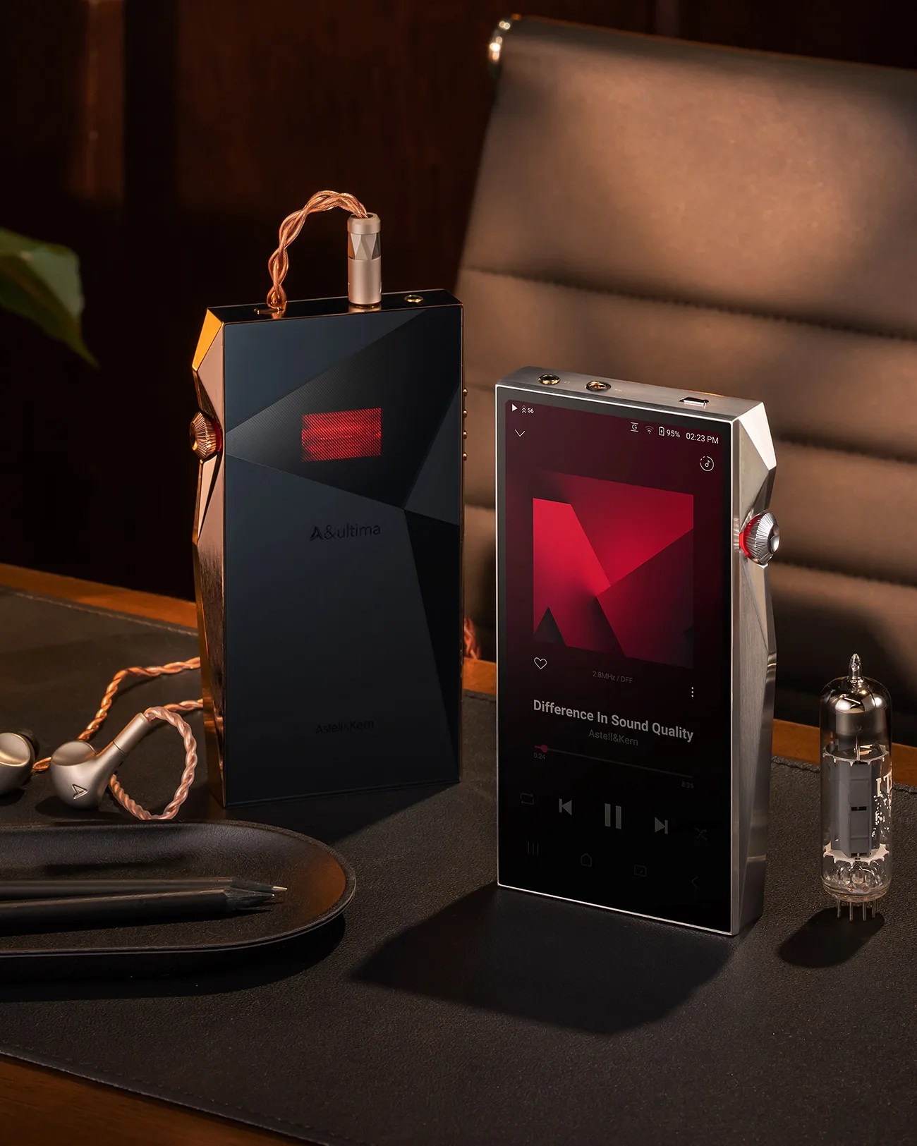 Two Astell&Kern portable music players, one black with copper cable and one silver with screen displaying "Difference In Sound Quality," on a desk.
