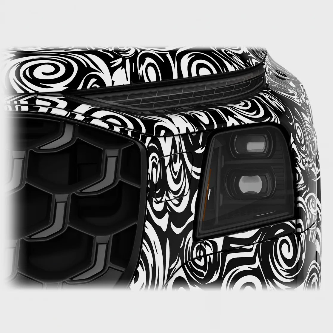 Close-up of a black and white swirled camouflaged car front corner showing a dark headlight and grille.