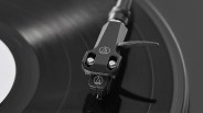 Close-up of a black turntable tonearm and stylus resting on a vinyl record.