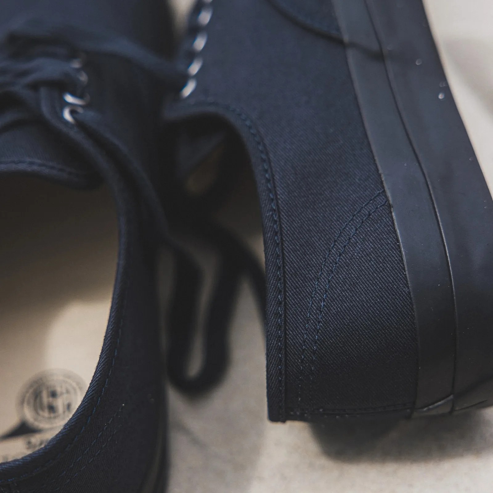 Close-up of black canvas sneakers showing stitching and rubber sole edge.