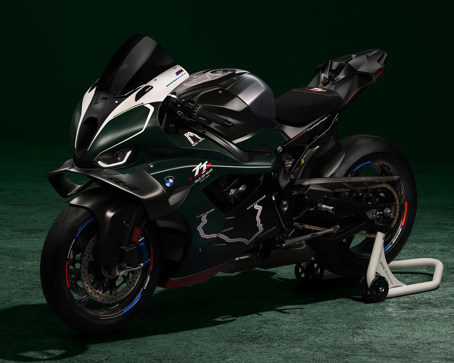 Dark green and black BMW sport motorcycle with Isle of Man TT race graphics on a green floor.