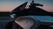 Close-up of a BMW motorcycle's side panel and handlebar against a dusk sky.
