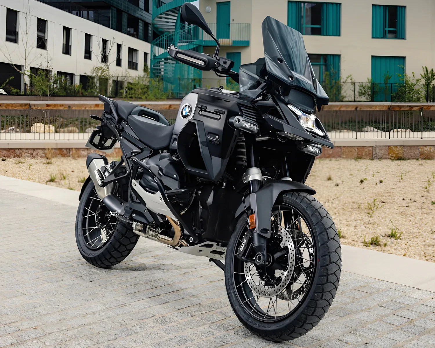 Black and silver BMW adventure motorcycle parked on a paved surface in front of a building.