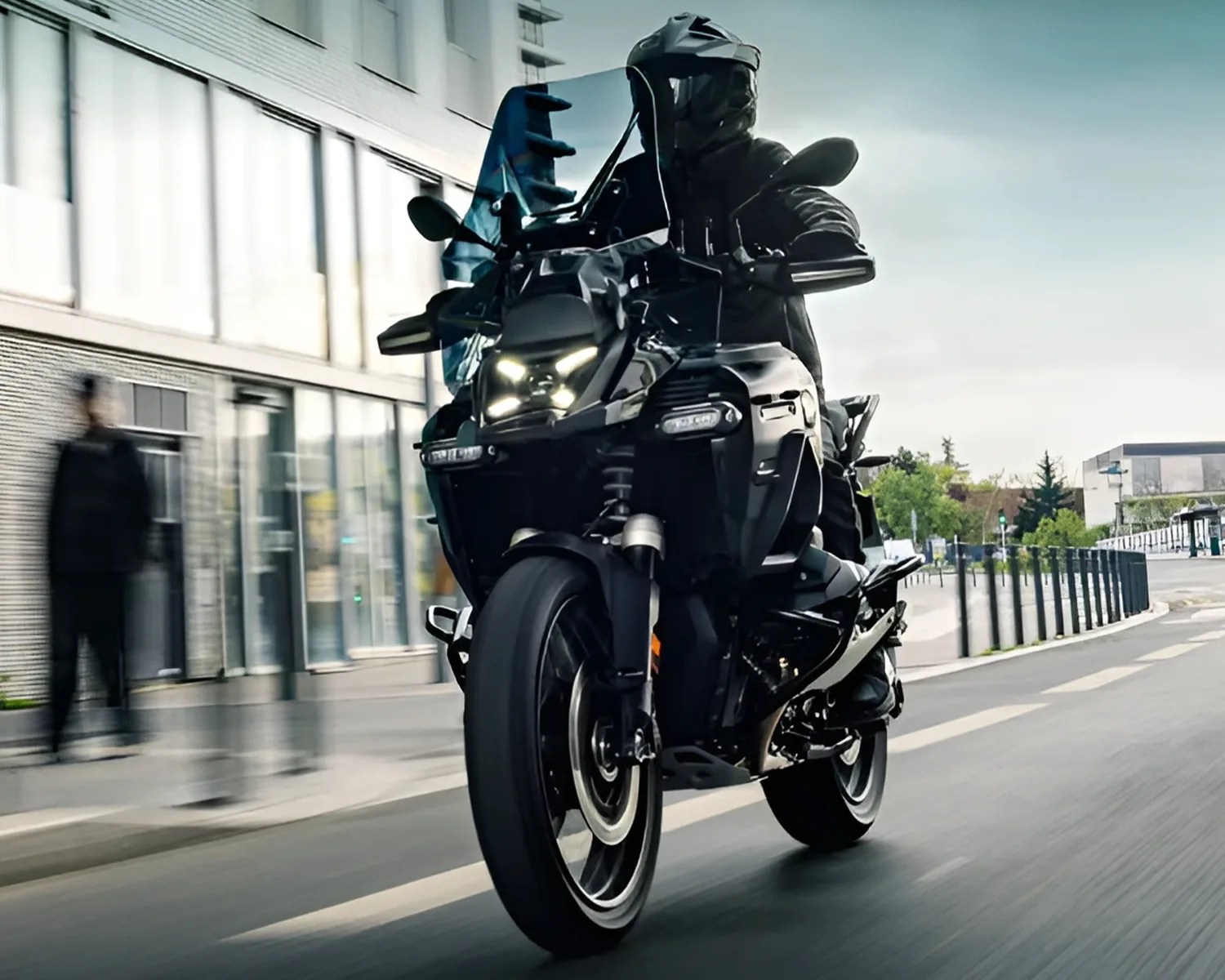 Black adventure motorcycle with LED headlights ridden on a city street.