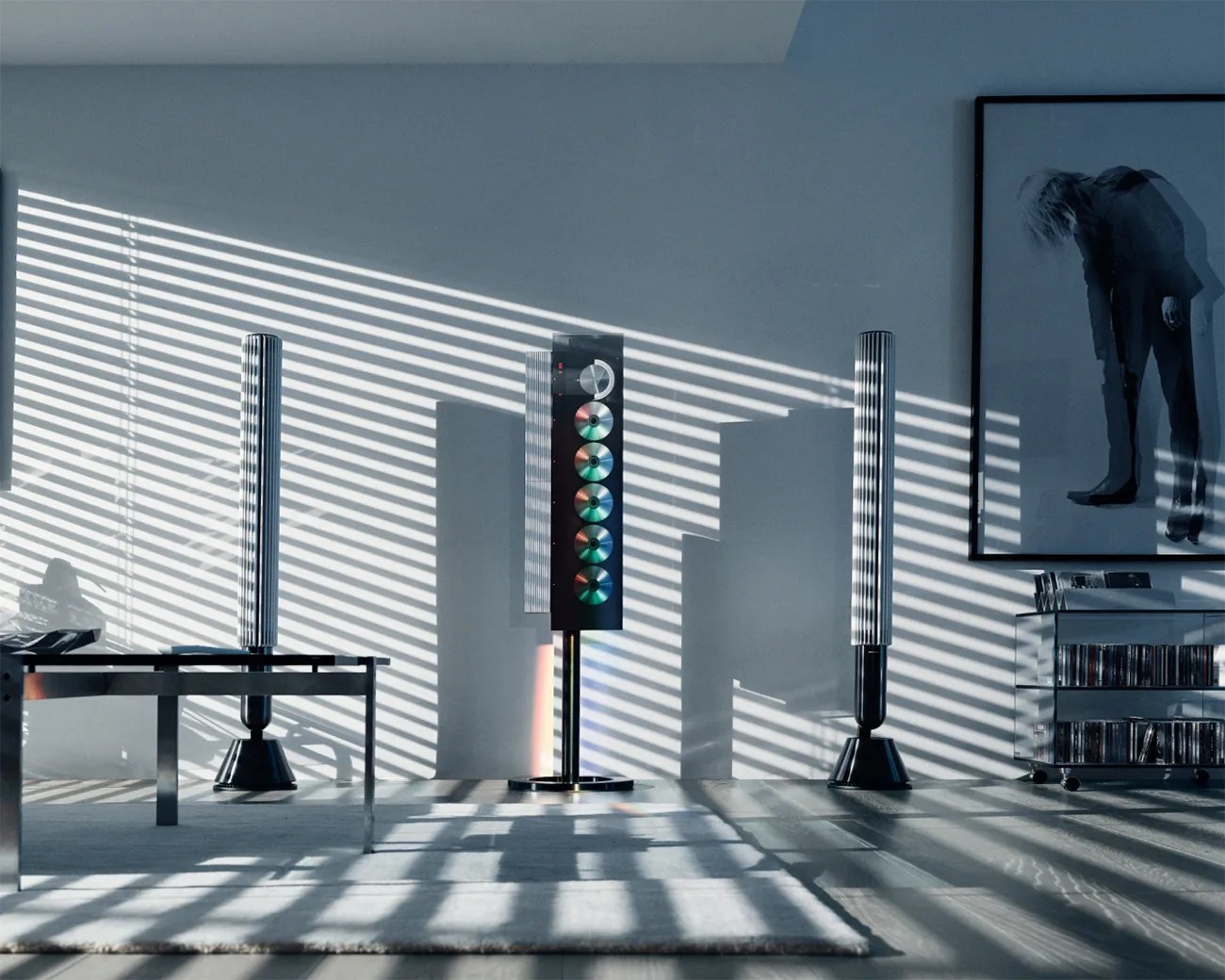 Modern living room with black tower speakers, a black metal table, a glass cabinet with CDs, and a large framed artwork on a gray wall.