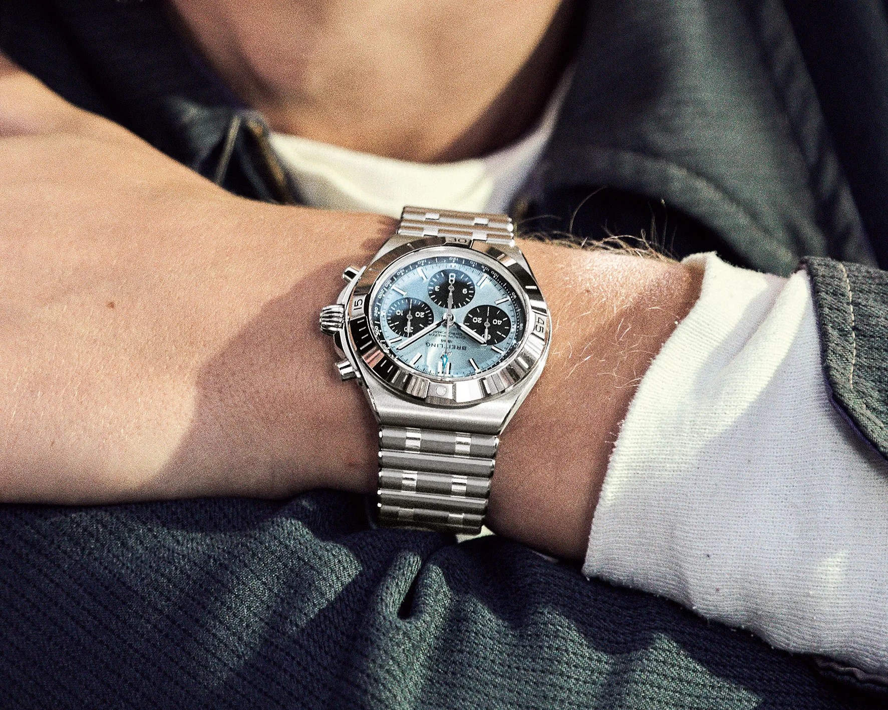 Silver metal chronograph wristwatch with light blue dial and black subdials worn on a wrist.