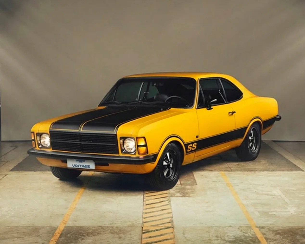 Yellow and black vintage Chevrolet SS muscle car parked indoors on a concrete floor.