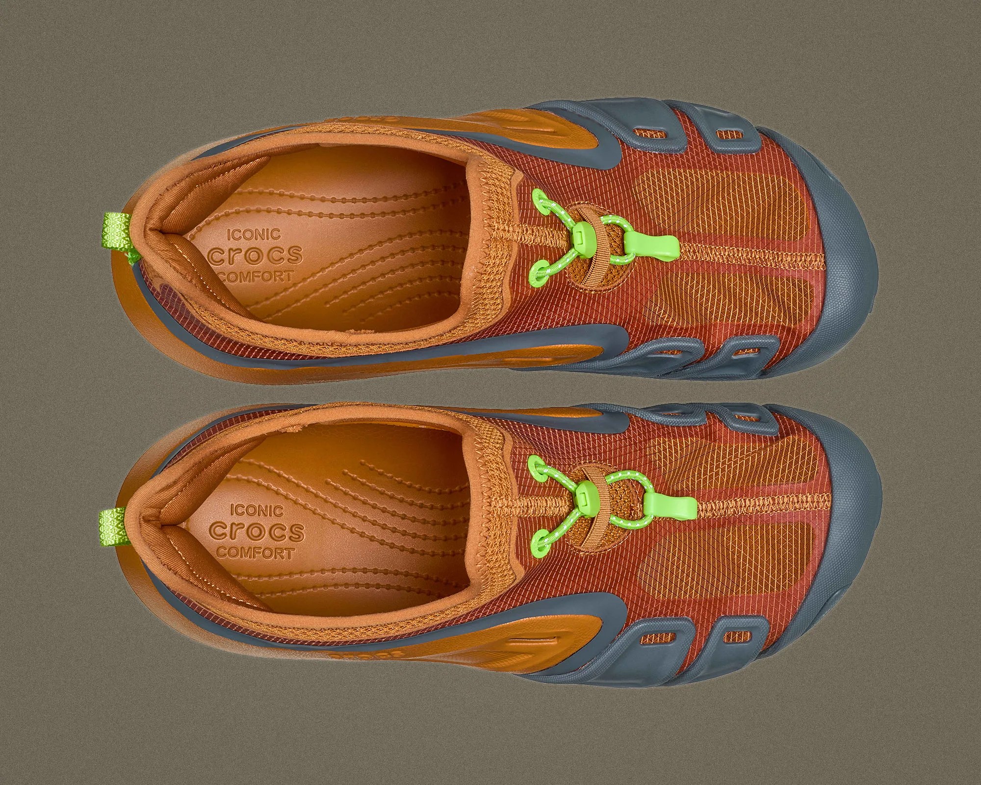 Pair of orange and gray Crocs shoes with green toggle laces and cushioned insoles labeled "Iconic Crocs Comfort.