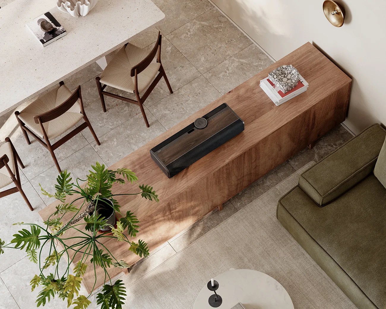 Wooden sideboard with a black and wood-tone speaker, potted plant, and stacked books in a living room.