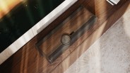 Wood-finished DALI soundbar with central circular control panel on a wooden cabinet.