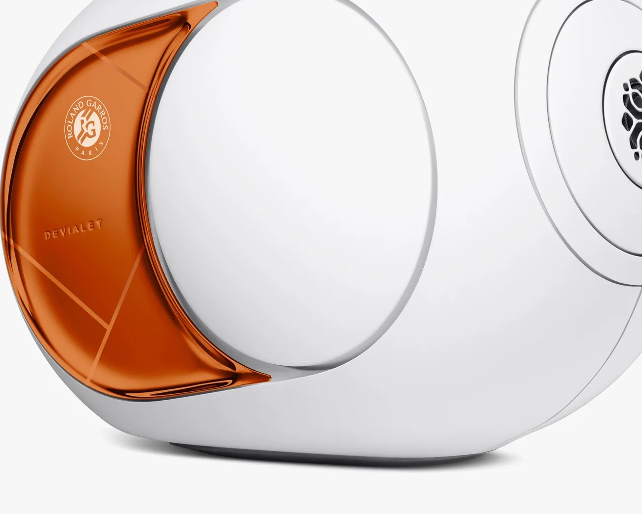 White speaker with an orange accent panel featuring "Roland Garros Paris" and "Devialet" logos.