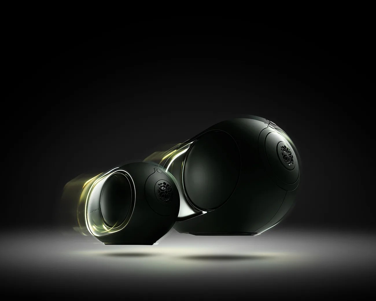 Pair of sleek black spherical speakers with illuminated edges floating against a dark background.