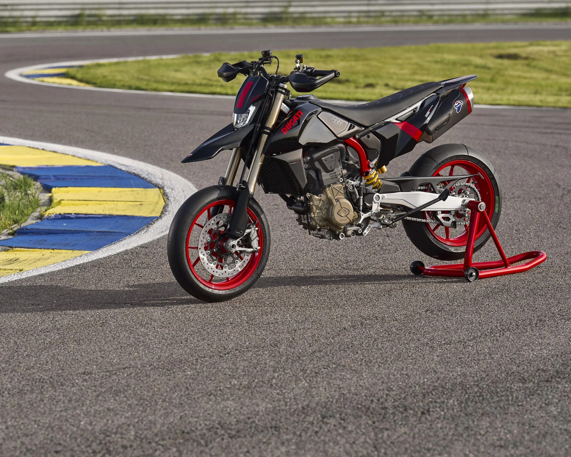 Black Ducati motorcycle with red wheels and red frame details on a racetrack.