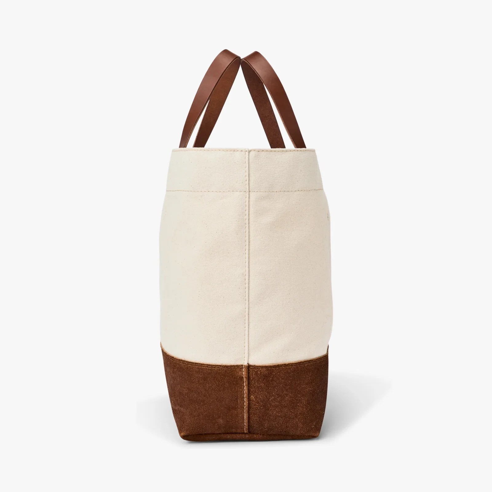 Beige canvas tote bag with brown suede bottom and brown leather handles, shown from the side.