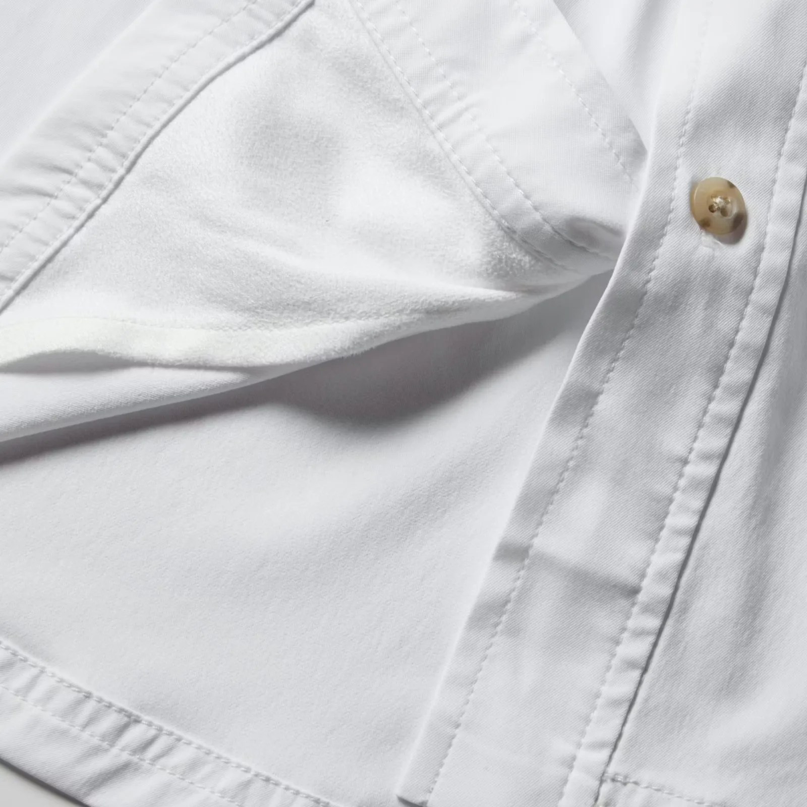 Close-up of a white shirt sleeve showing soft inner fabric and a beige button on the cuff.