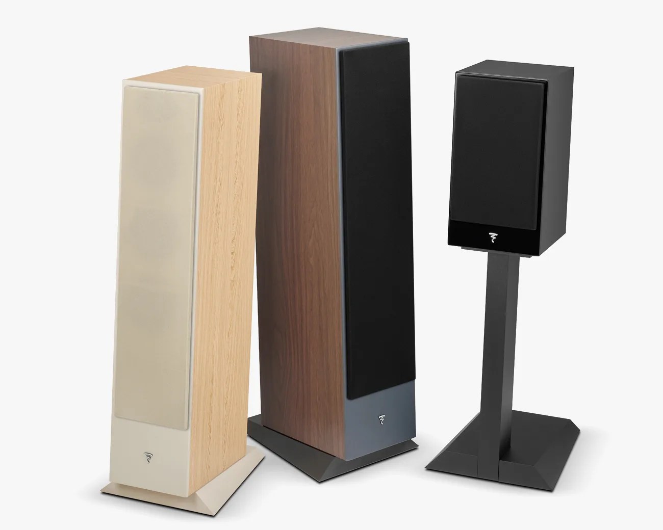 Three modern speakers with fabric covers, one beige with light wood, one dark wood, and one black on a black stand.