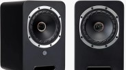 Pair of black bookshelf speakers with silver trim around the central cone and front bass ports.
