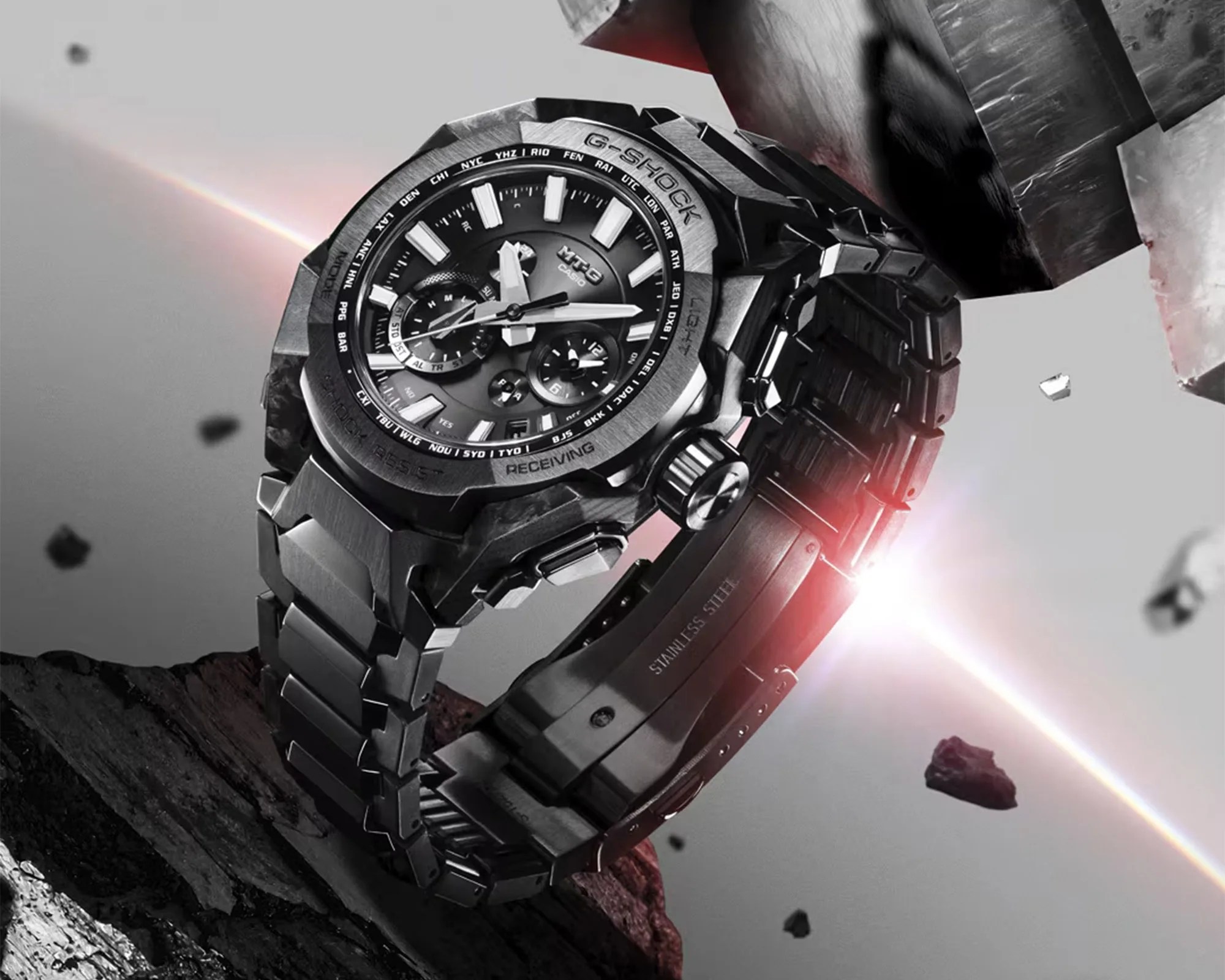Black and silver Casio G-Shock MT-G wristwatch with metal band and multiple dials on a rocky surface.