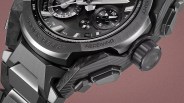 Close-up of a black and silver rugged wristwatch with multiple dials and buttons, showing "SHOCK RESIST" and "RECEIVING" engraved on the bezel.