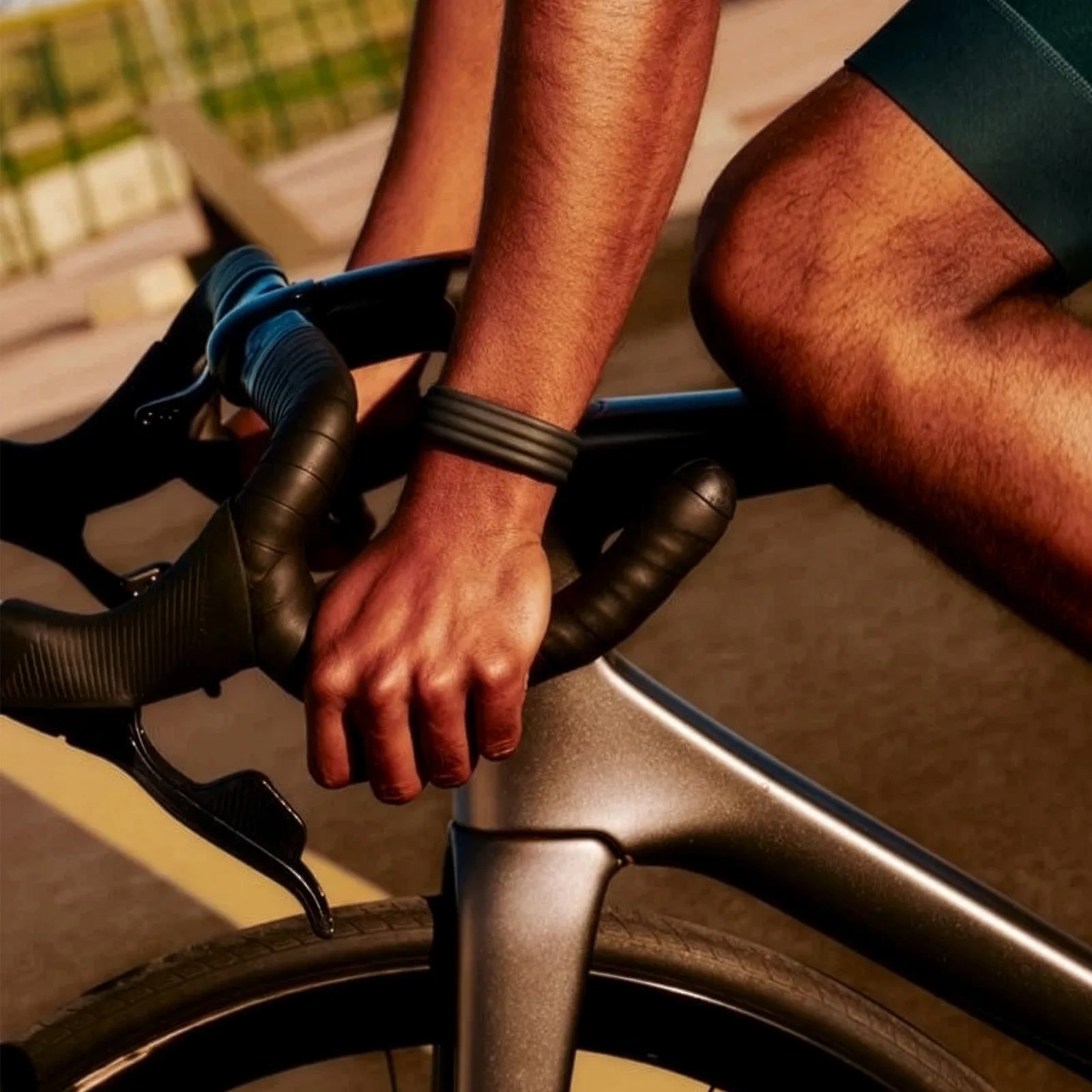 Close-up of a person gripping black drop handlebars on a matte gray road bike.