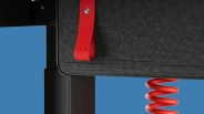 Close-up of a black felt panel with a red fabric loop and a red coiled cable hanging below.