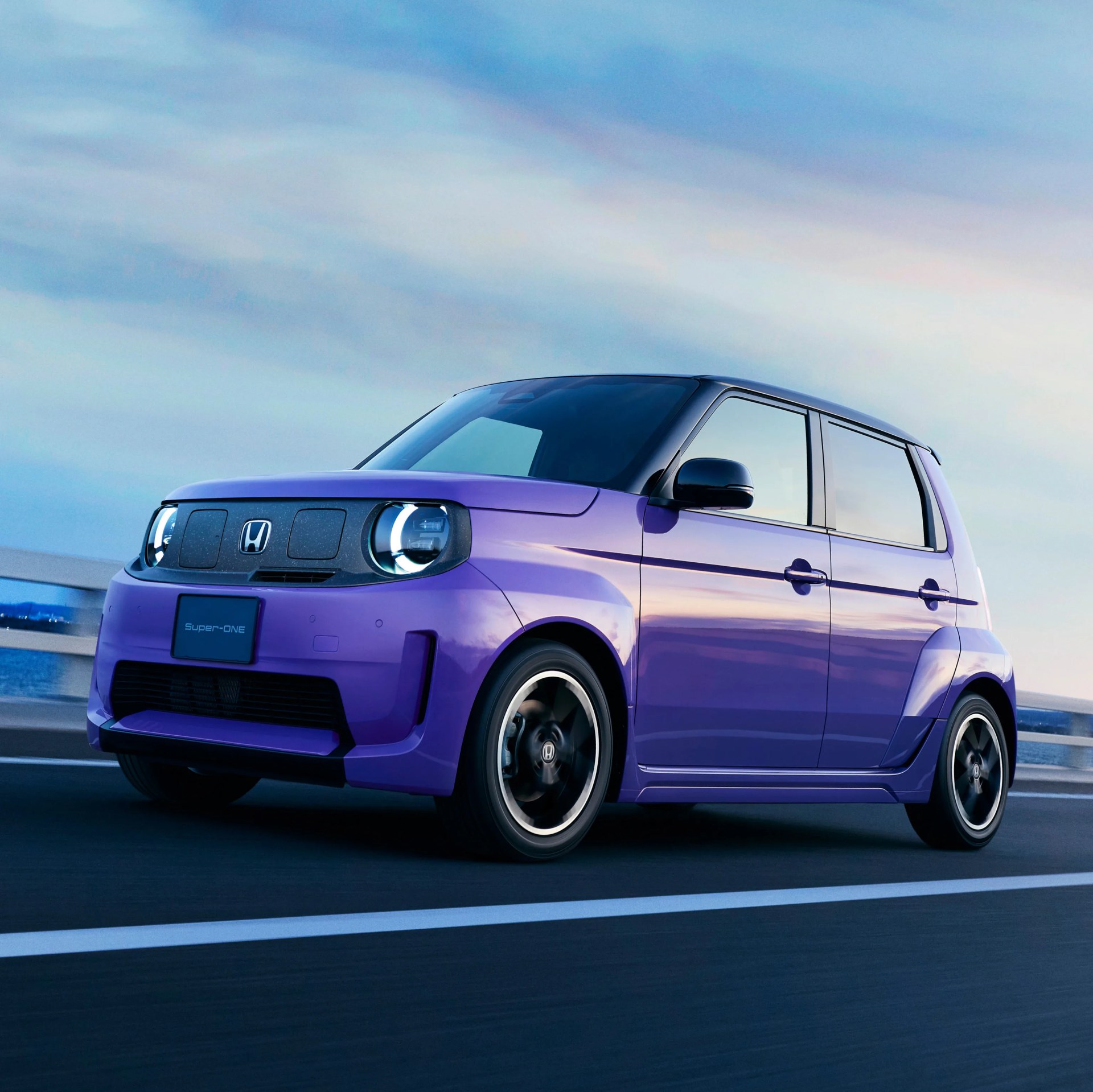 Purple Honda compact car with black roof and round LED headlights on a road at dusk.