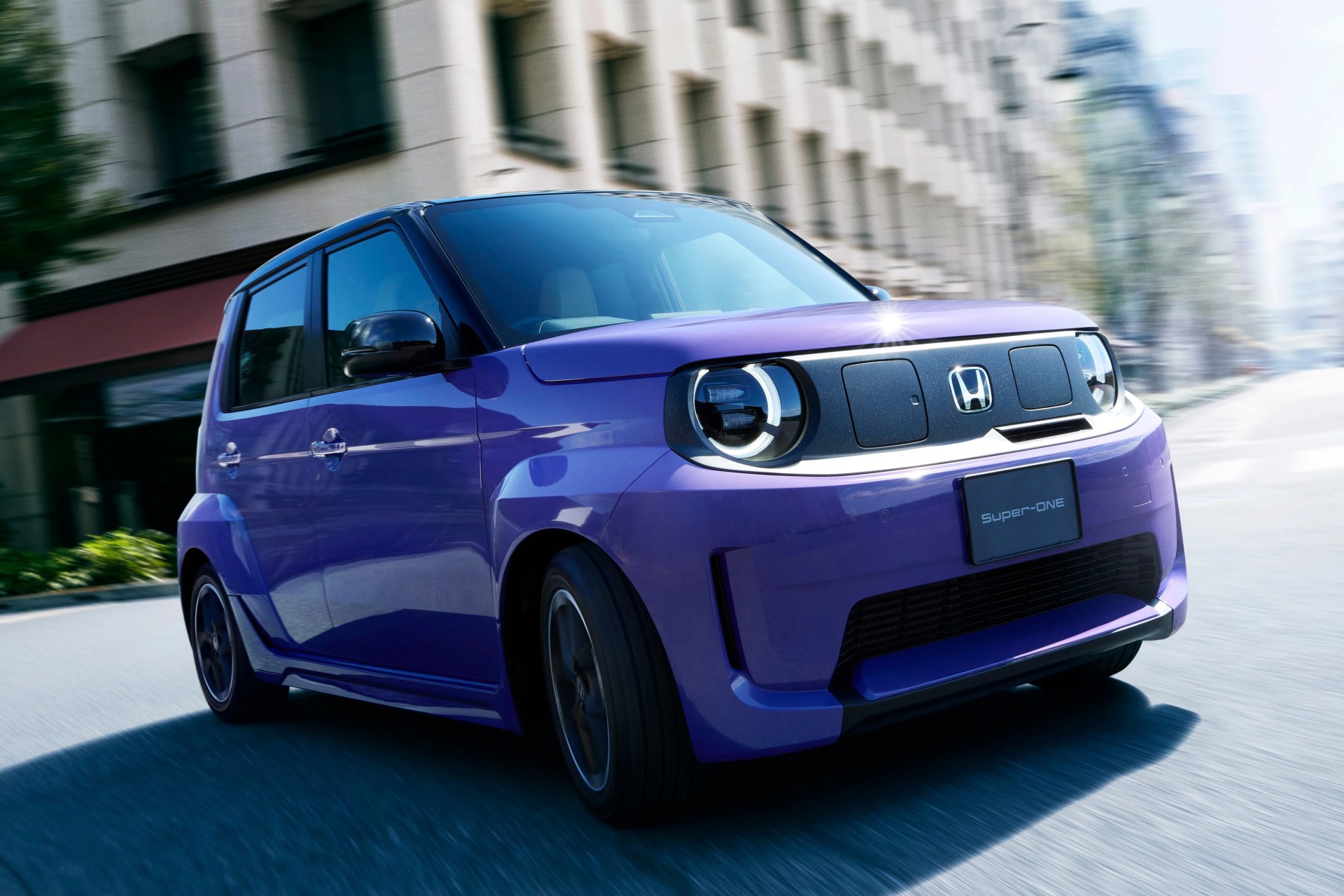 Purple compact Honda car with black roof and round LED headlights driving on a city street.