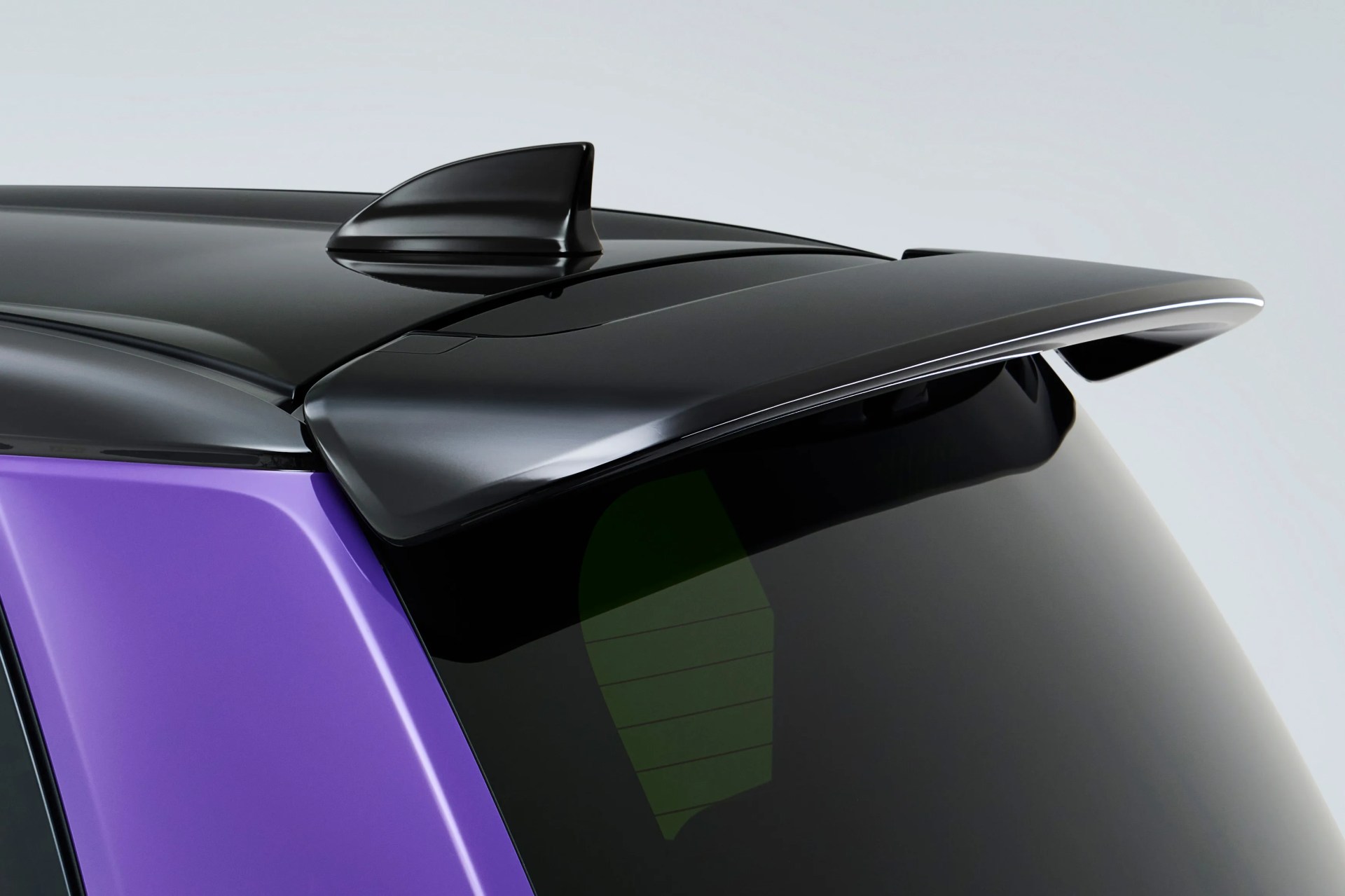 Glossy black shark fin antenna and rear spoiler on a purple car roof.
